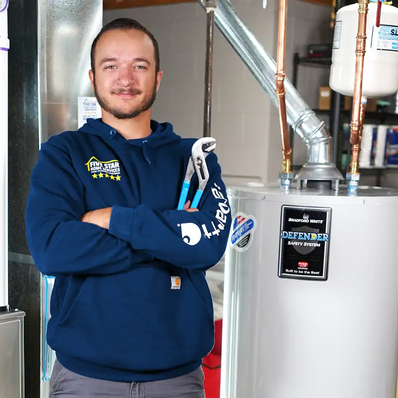 Plumber holding a wrench standing next to a water heater