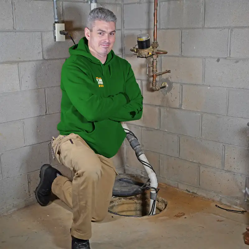 Plumber kneeling next to a sump pump