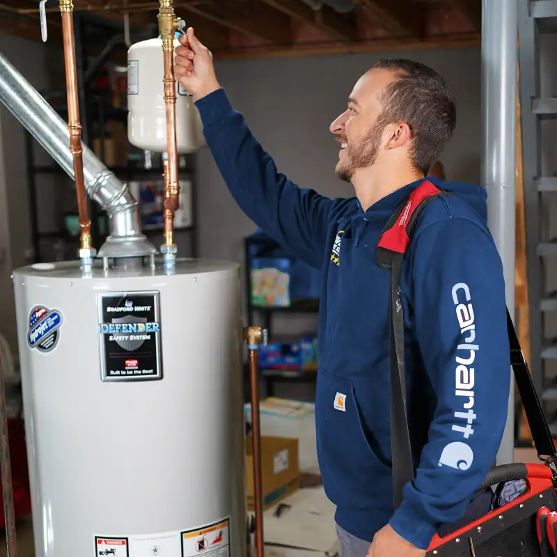 Plumber next to a water heater checking a gauge